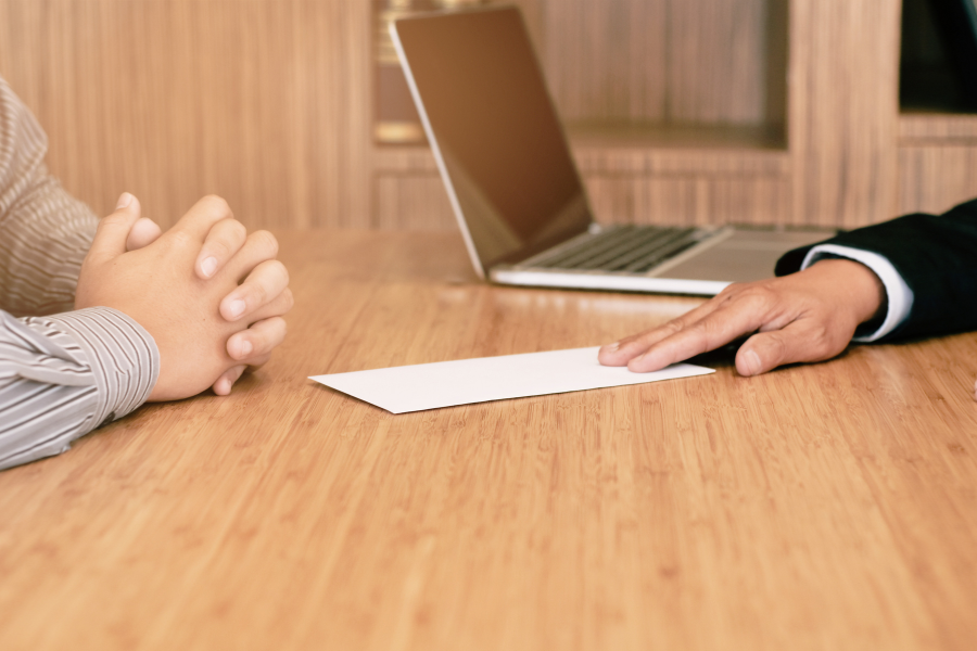 Reunión de despido en la oficina, una persona entrega una carta a otra sobre la mesa, simbolizando un despido formal y respetuoso